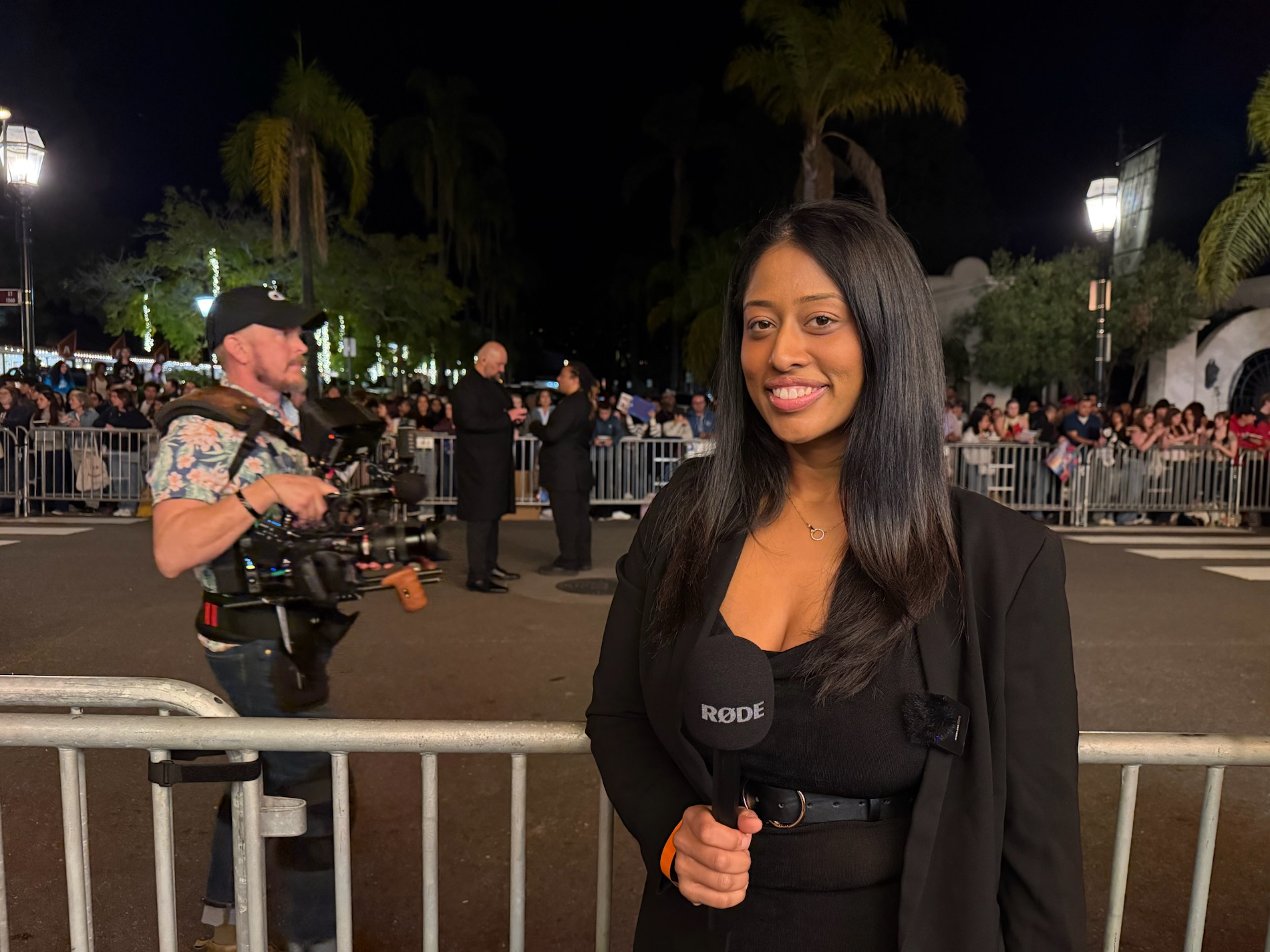 Sesha at a red-carpet event with a production camera in the background